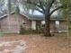 Exterior view of a single story home with wood siding and front yard with tree at 261 Acacia Walk, Lake Wales, FL 33898