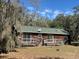 Charming home exterior with a wooded backdrop, complemented by an expansive backyard at 261 Acacia Walk, Lake Wales, FL 33898