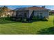 Backyard view of the home with a screened lanai and lush lawn at 3014 Ashton Palms Dr, Lake Wales, FL 33859