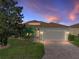 Charming single-story home with brick driveway, attached garage, and colorful dusk sky at 3014 Ashton Palms Dr, Lake Wales, FL 33859