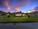 A picturesque view of the home's rear with a screened lanai and serene water view at dusk at 3014 Ashton Palms Dr, Lake Wales, FL 33859