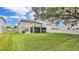 Expansive backyard featuring lush lawn, mature trees, screened lanai with table and chairs, and white fence at 3217 La Salle St, Winter Haven, FL 33884