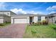 Charming single-story home featuring a two-car garage, blue front door, brick driveway, and well-maintained landscaping at 336 Summer Squall Rd, Davenport, FL 33837