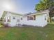 Exterior shot of the white home with decorative shutters, green lawn, and landscaping at 3736 Knights Station Rd, Lakeland, FL 33810