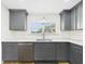 Modern kitchen showcasing gray cabinets, white backsplash, and stainless steel dishwasher and sink at 3736 Knights Station Rd, Lakeland, FL 33810