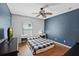 Bedroom with ceiling fan, wood floors, blue accent wall, and natural light from window at 3905 Osprey Pointe Cir, Winter Haven, FL 33884