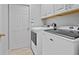 Laundry room with washer and dryer units, white cabinets, and a door at 3905 Osprey Pointe Cir, Winter Haven, FL 33884