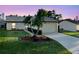 Charming single-story home featuring a well-manicured lawn and a two-car garage at sunset at 4016 Cypress S Lndg, Winter Haven, FL 33884