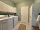 Clean laundry room featuring modern white washer, dryer, overhead cabinets, and a side storage cabinet at 4088 Dunmore Dr, Lake Wales, FL 33859
