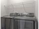 Modern laundry room with gray, front-load washer and dryer and wire rack shelf at 438 Monroe Cir, Davenport, FL 33896