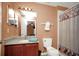 Bathroom includes a vanity with granite countertop, toilet and shower with decorative curtains at 451 Montara Dr, Davenport, FL 33897