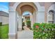 Charming arched entryway with lush greenery and a welcoming pathway leading to the front door at 451 Montara Dr, Davenport, FL 33897