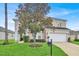 Charming two-story home featuring a well-manicured lawn, a two-car garage, and a nicely landscaped yard with mature tree at 451 Montara Dr, Davenport, FL 33897