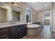 Bright bathroom featuring a soaking tub, double vanity, walk-in shower, and wood-look tile flooring at 4717 Emerald Palms Ct, Winter Haven, FL 33884
