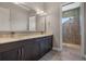 Bathroom vanity with double sinks, granite countertop, dark cabinets, and a tiled walk-in shower at 4717 Emerald Palms Ct, Winter Haven, FL 33884