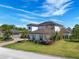 Elegant two-story home with lush landscaping, palm trees, and a separate garage, creating a welcoming curb appeal at 4717 Emerald Palms Ct, Winter Haven, FL 33884