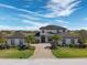 Striking two-story home with a symmetrical facade, lush landscaping, and a brick driveway leading to the front entrance at 4717 Emerald Palms Ct, Winter Haven, FL 33884