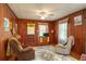 Vintage living room with wood paneling, ceiling fan, and cozy recliners on a floral rug at 555 Morrel Ave, Lake Wales, FL 33859