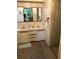 Bathroom features a double vanity, wallpaper, carpet flooring, large mirror, and a doorway leading into another room at 6515 Raintree Ne Ln, Winter Haven, FL 33881