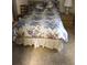 Cozy bedroom featuring a bed with floral bedding, a nightstand, and beige walls with coordinating carpet at 6515 Raintree Ne Ln, Winter Haven, FL 33881