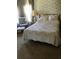 This bedroom features a floral comforter, a cushioned chair and ottoman, and neutral wallpaper at 6515 Raintree Ne Ln, Winter Haven, FL 33881