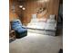 Inviting living room features a floral sofa, blue recliner, wood paneling and neutral carpet at 6515 Raintree Ne Ln, Winter Haven, FL 33881
