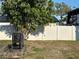 Backyard featuring a lush tree, a white vinyl fence, and chairs on a wood dock at 707 Great Barford St, Auburndale, FL 33823