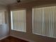 Bright room featuring hardwood floors, neutral walls, and large windows with vertical blinds at 707 Great Barford St, Auburndale, FL 33823