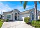 Attractive single-story home featuring a two-car garage, lush landscaping, and a stucco exterior with a welcoming arched entryway at 908 Orista Dr, Davenport, FL 33897