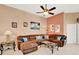 Comfortable living room with a large brown sofa, a ceiling fan, neutral walls, and decorative artwork at 908 Orista Dr, Davenport, FL 33897