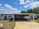 Charming home with a boat parked in the carport, under a bright blue sky at 121 Bonnie Dr, Auburndale, FL 33823