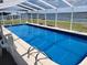 Inviting screened-in pool with ladders and clear blue water, dock in distance at 121 Bonnie Dr, Auburndale, FL 33823