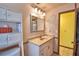 Bathroom featuring beige vanity, mirror, sconces and storage with a view into yellow hallway at 122 Wgto Tower Rd, Lake Alfred, FL 33850