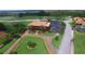 Aerial view of a golf course with lush landscaping, golf carts and building with a manicured driveway at 1402 Colonial Ct, Winter Haven, FL 33884