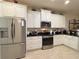 Modern kitchen featuring stainless steel appliances, granite countertops, and white cabinetry at 1402 Colonial Ct, Winter Haven, FL 33884