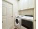 Well-equipped laundry room with a modern washer, dryer, and overhead storage cabinets at 1402 Colonial Ct, Winter Haven, FL 33884
