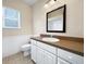 Bathroom featuring white vanity, sink, large mirror, window for natural light and a toilet at 1409 Berkley Ct, Winter Haven, FL 33880