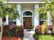 Close-up of front door with glass accents, flanked by palm trees and decorative bushes at 1409 Berkley Ct, Winter Haven, FL 33880