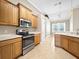 Well-lit kitchen features stainless steel appliances, tile floor, and wood cabinetry at 1409 Berkley Ct, Winter Haven, FL 33880