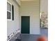 Side entrance to home with light green siding, dark green door and shutters, and white trimmed windows at 167 Bonnie Dr, Auburndale, FL 33823