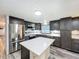 Well-lit kitchen with dark cabinets, stainless steel appliances, and center island with white countertop at 167 Bonnie Dr, Auburndale, FL 33823