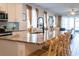 Close-up of kitchen island featuring a granite countertop, bar seating, modern faucet, and view of the open-concept living area at 169 Summershore Dr, Auburndale, FL 33823