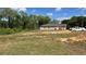 View of the back of the home showing a large yard, wooded backdrop and parked cars at 214 Brook Ln, Polk City, FL 33868