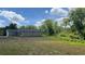 View of home, backyard with lawn and abundant trees under a cloudy blue sky at 214 Brook Ln, Polk City, FL 33868
