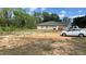 View of the back of the home showing a large, red dirt yard, and parked cars at 214 Brook Ln, Polk City, FL 33868