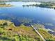 An aerial view of a lake with a long wooden dock surrounded by lush greenery and blue waters at 218 Omaha St S S St, Lake Hamilton, FL 33851