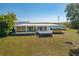 Back of yellow home featuring a metal roof and a deck, set in a spacious grassy yard at 225 Wes Mann Rd, Babson Park, FL 33827