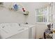 Clean laundry room with a washer, dryer, shelving, and a window for natural light at 247 Cobalt Dr, Kissimmee, FL 34758