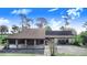 Unique home featuring a carport with stone columns and a spacious driveway surrounded by mature trees at 2750 W Lake Hamilton Dr, Winter Haven, FL 33881