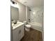 Bright bathroom with a white vanity, marble-look tiled shower and wood-look flooring at 3120 Oleander Dr, Indian Lake Estates, FL 33855